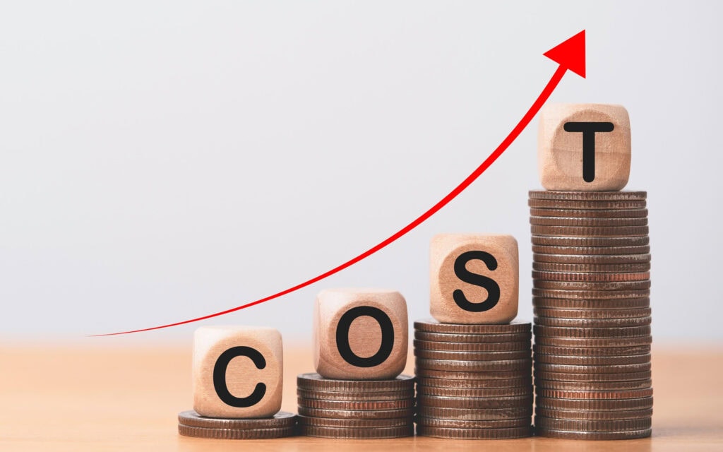 wooden blocks spelling 'cost' on stacks of coins representing $500 loans