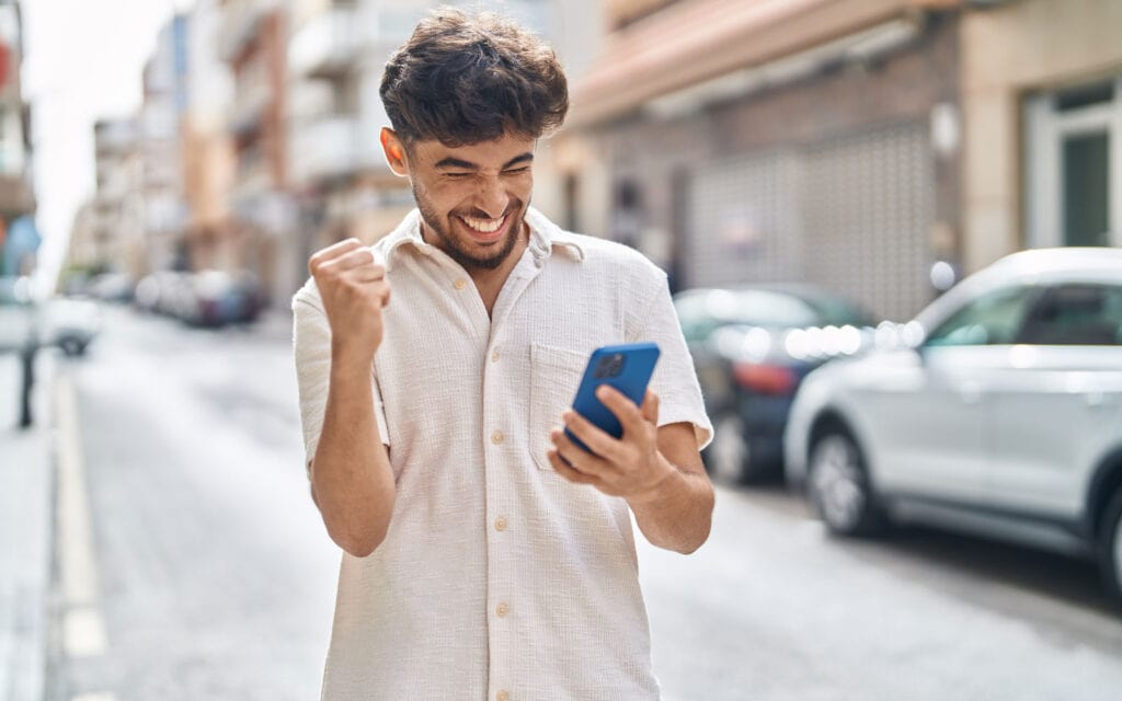 a guy checking his phone and happy he his 50k loan was approved