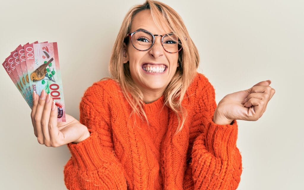 woman in orange jumper holding cash